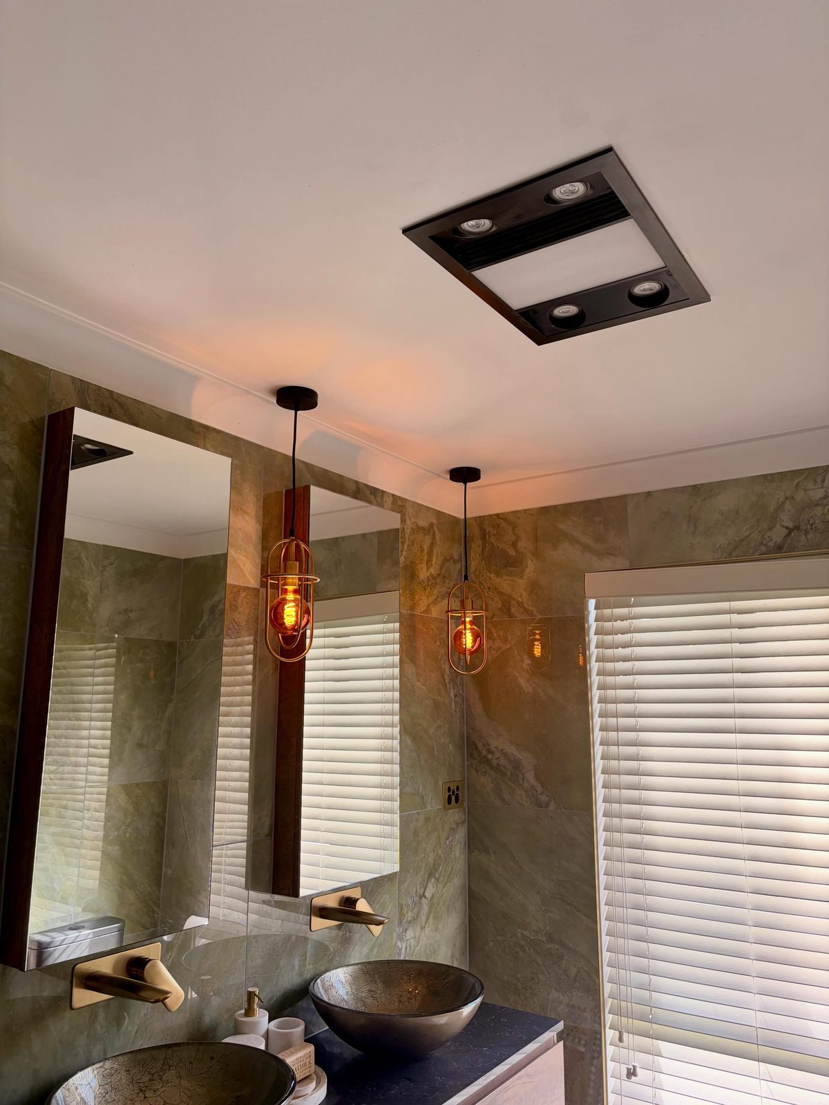 Copper pendant lights and a ceiling exhaust heater in a renovated stone bathroom