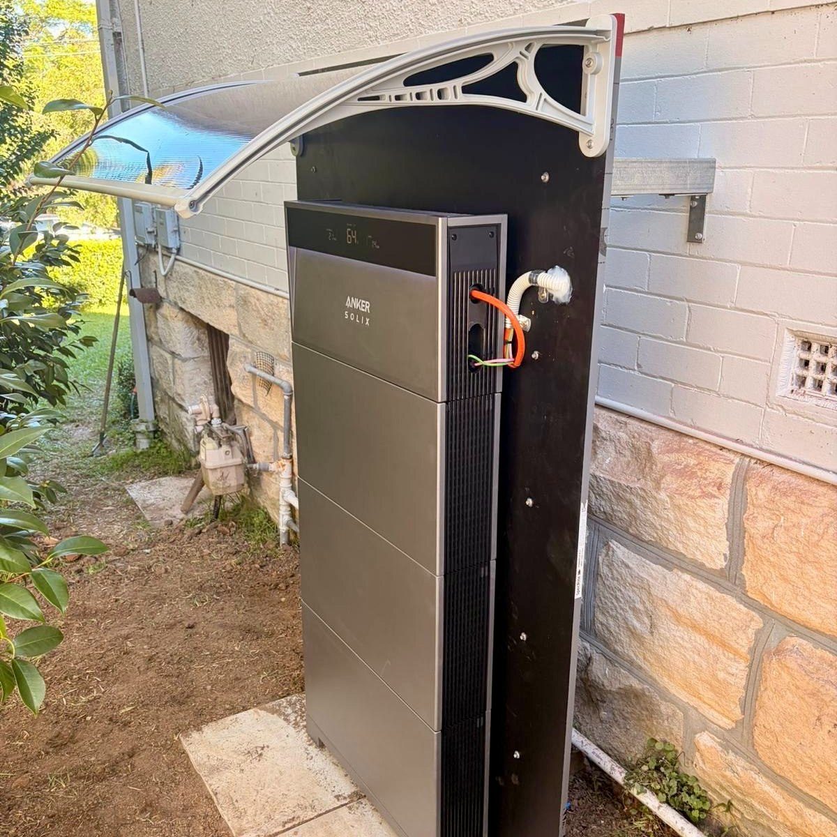 Home battery and backup power system installed outside against a brick wall
